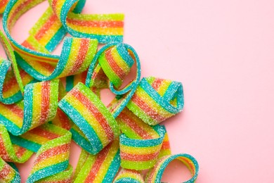 Photo of Tasty rainbow sour belts on pink background, top view. Space for text