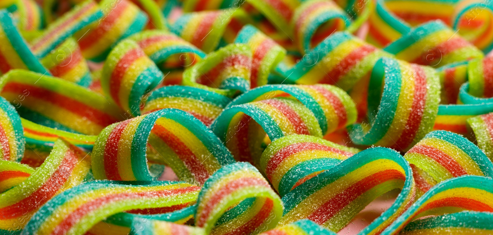 Photo of Tasty rainbow sour belts as background, closeup