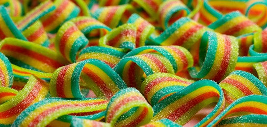 Photo of Tasty rainbow sour belts as background, closeup