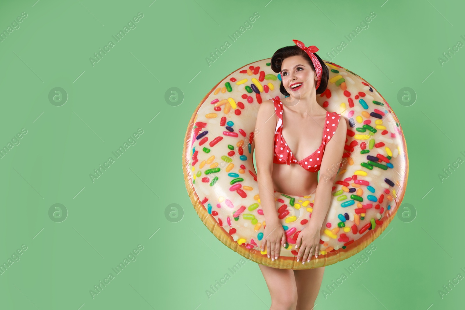 Photo of Pin-up woman in bikini with inflatable ring on green background