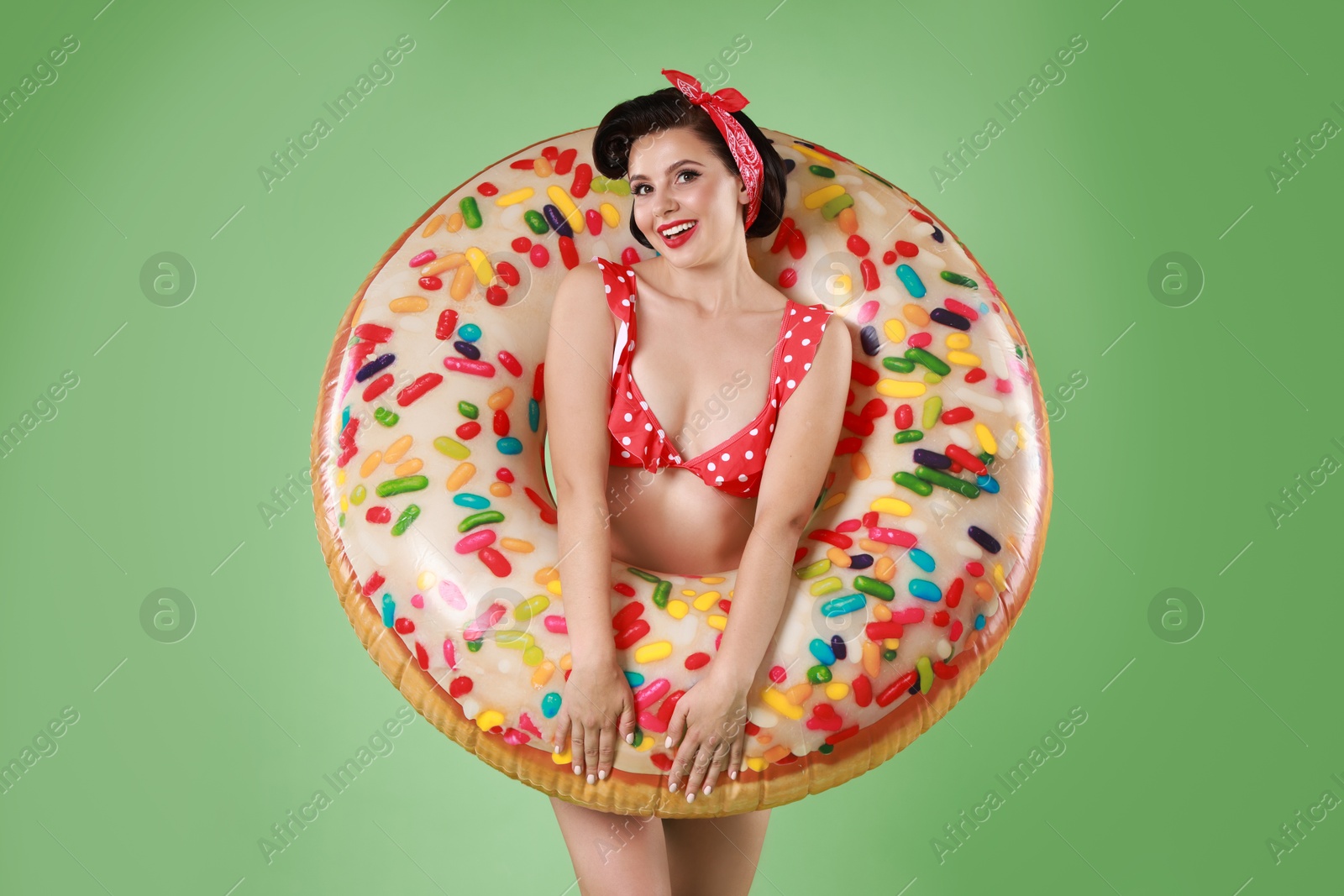 Photo of Pin-up woman in bikini with inflatable ring on green background