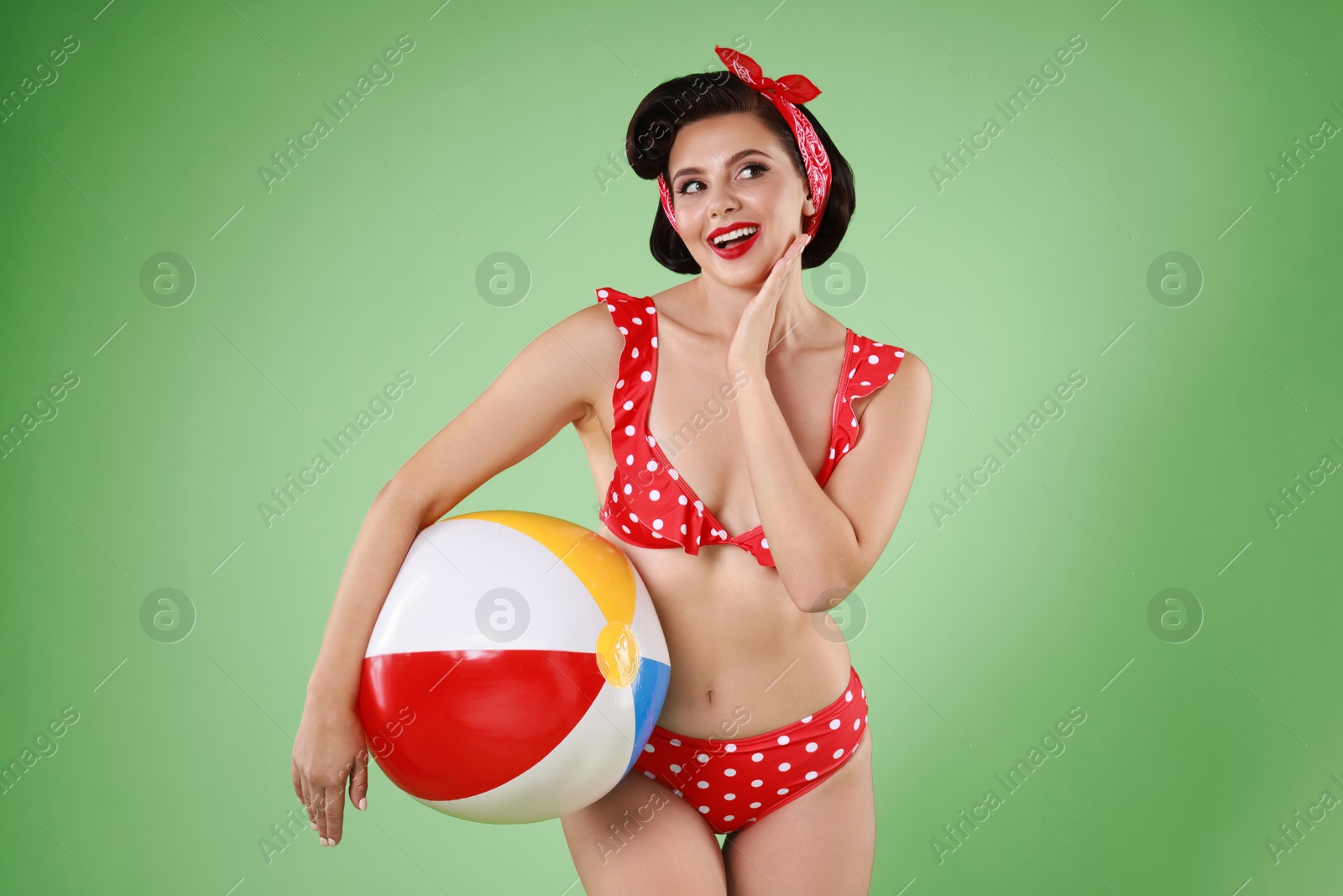 Photo of Pin-up woman in bikini with inflatable ball on green background