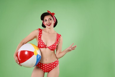 Photo of Pin-up woman in bikini with inflatable ball on green background, space for text