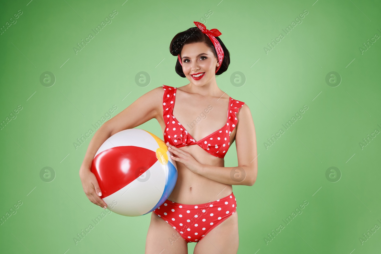 Photo of Pin-up woman in bikini with inflatable ball on green background