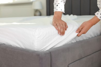 Photo of Woman changing clean bed linens at home, closeup