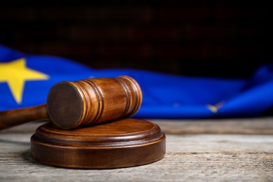 Photo of Judge's gavel and European Union flag on wooden table against black background, closeup. Space for text