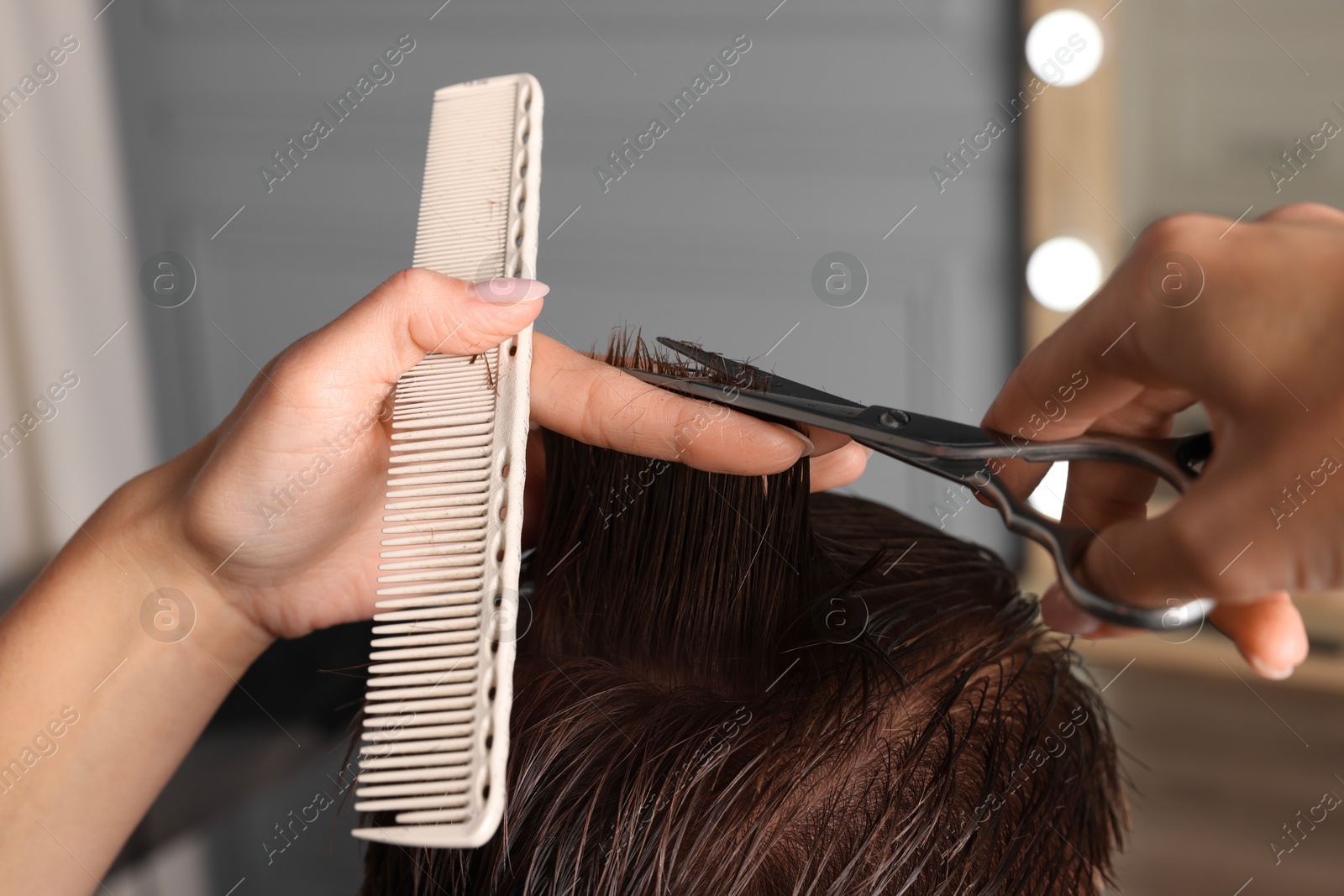 Photo of Professional hairdresser cutting client's hair with scissors in barbershop, closeup