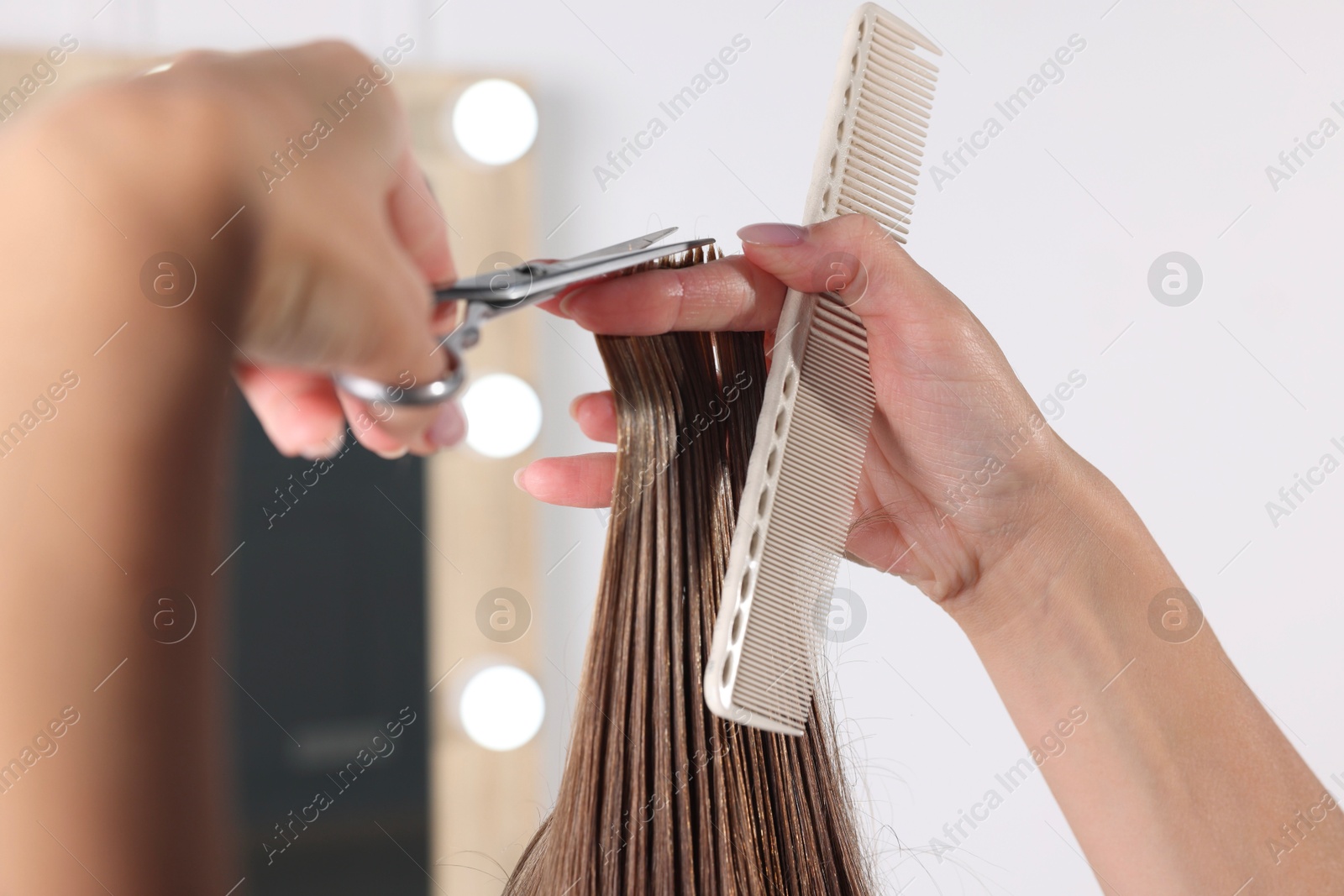 Photo of Hairdresser cutting client's hair with scissors in salon, closeup