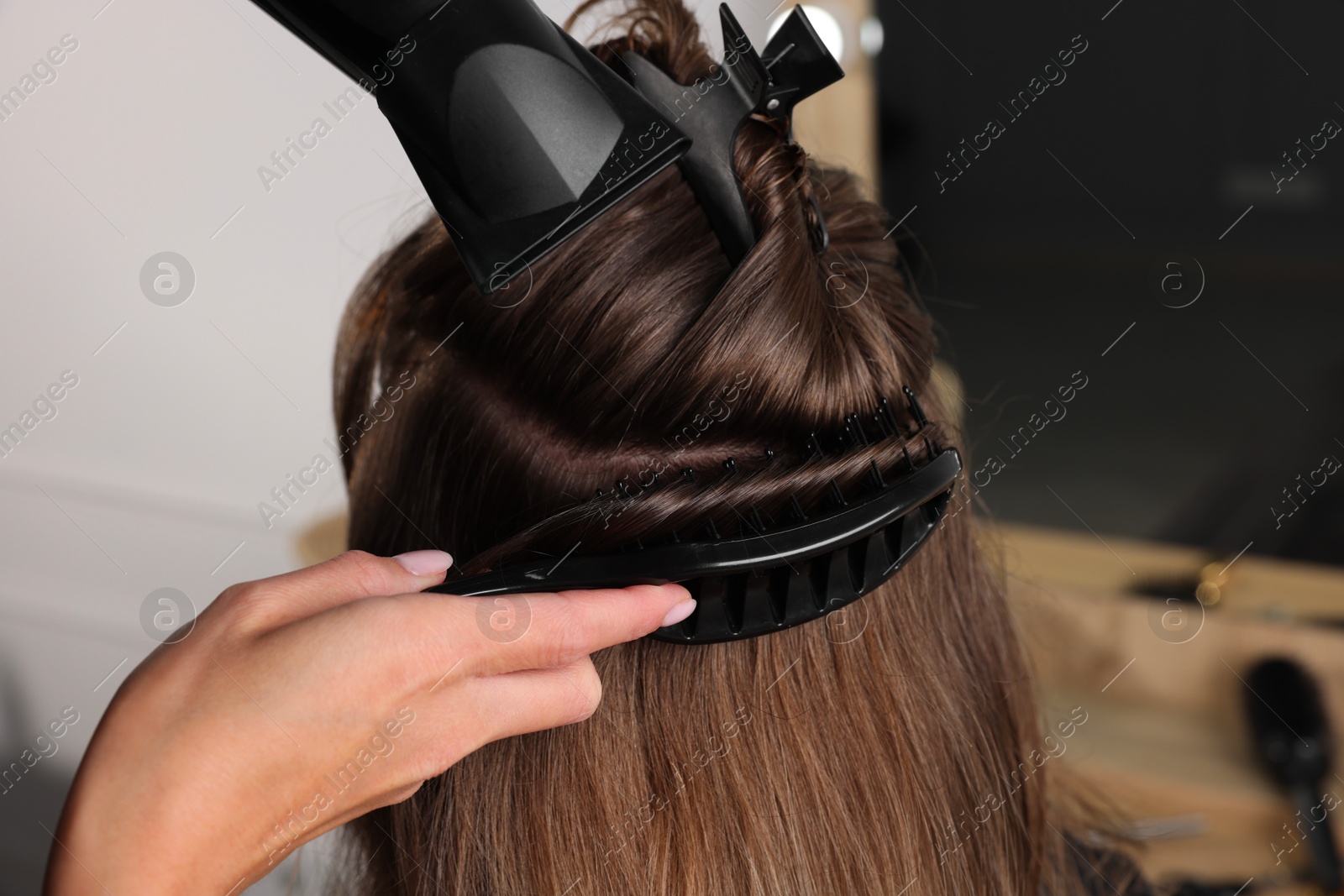 Photo of Hairdresser blow drying client's hair in salon, closeup