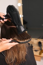 Photo of Hairdresser blow drying client's hair in salon, closeup