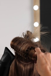 Photo of Hairdresser blow drying client's hair in salon, closeup