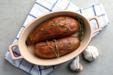 Photo of Tasty cooked sweet potatoes served with thyme on light grey table, top view