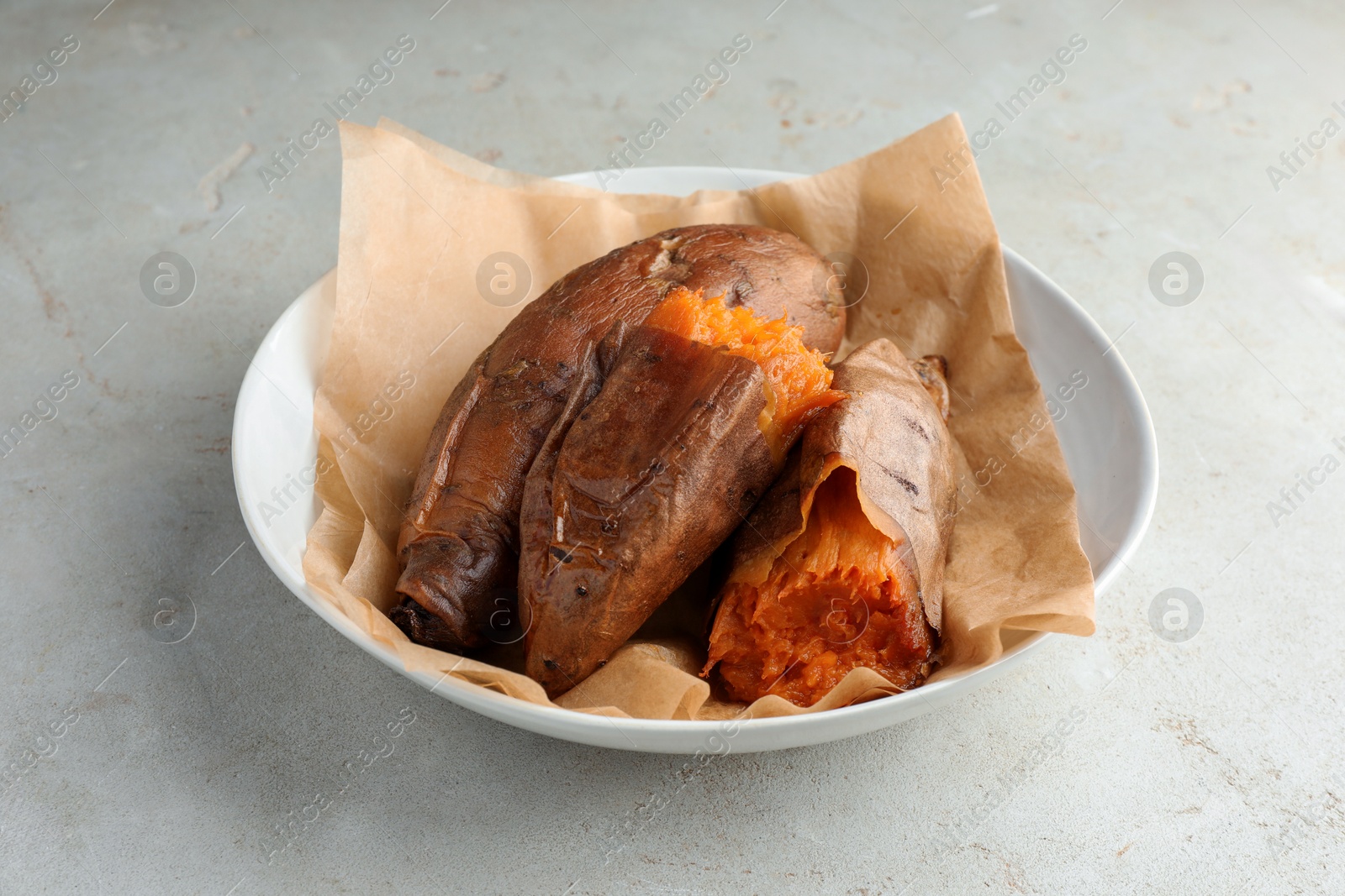 Photo of Tasty cooked sweet potatoes served on light grey table