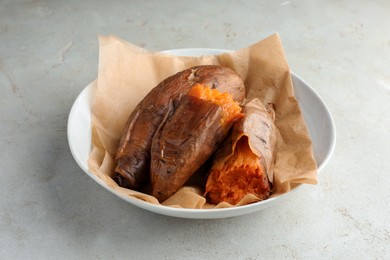 Tasty cooked sweet potatoes served on light grey table