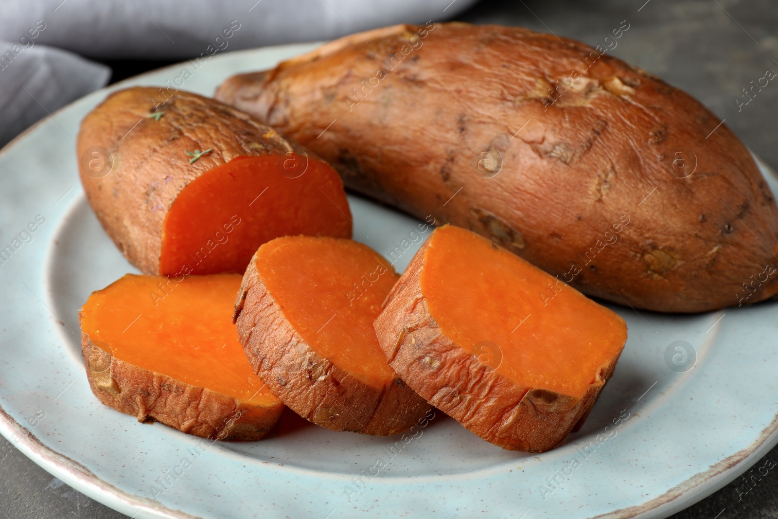 Photo of Tasty cooked sweet potatoes served on grey table, closeup