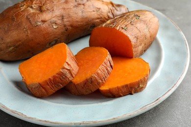 Photo of Tasty cooked sweet potatoes served on grey table, closeup