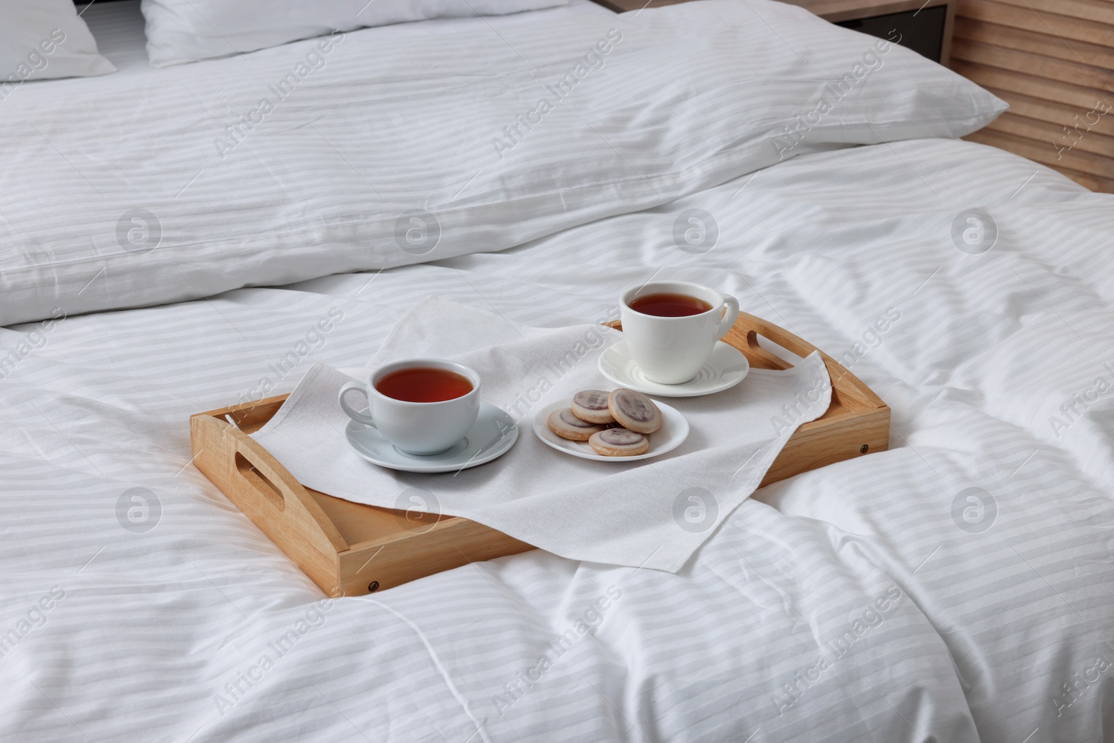 Photo of Breakfast tray on bed with beautiful linens indoors