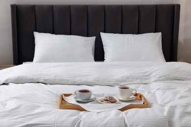 Photo of Breakfast tray on bed with beautiful linens indoors