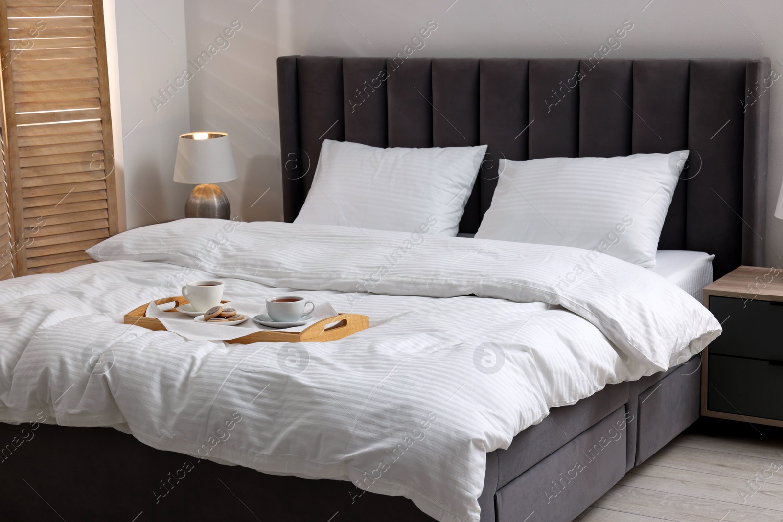 Photo of Breakfast tray on bed with beautiful linens indoors