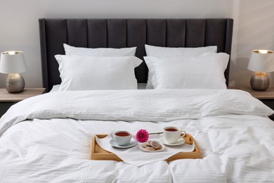 Photo of Breakfast tray on bed with beautiful linens indoors