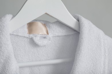 Photo of Clean terry bathrobe on grey background, closeup