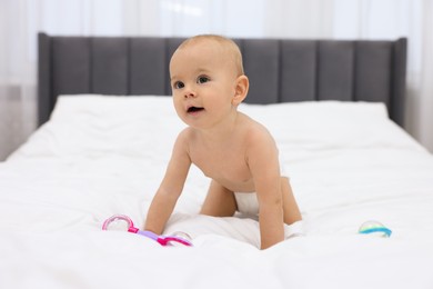 Photo of Cute little baby with rattles on bed indoors