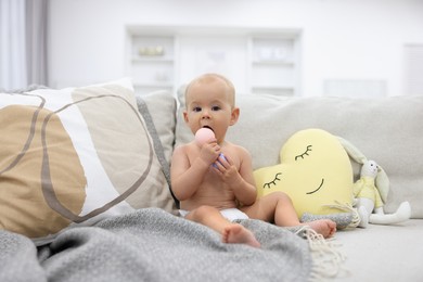 Photo of Cute little baby with rattle on sofa indoors