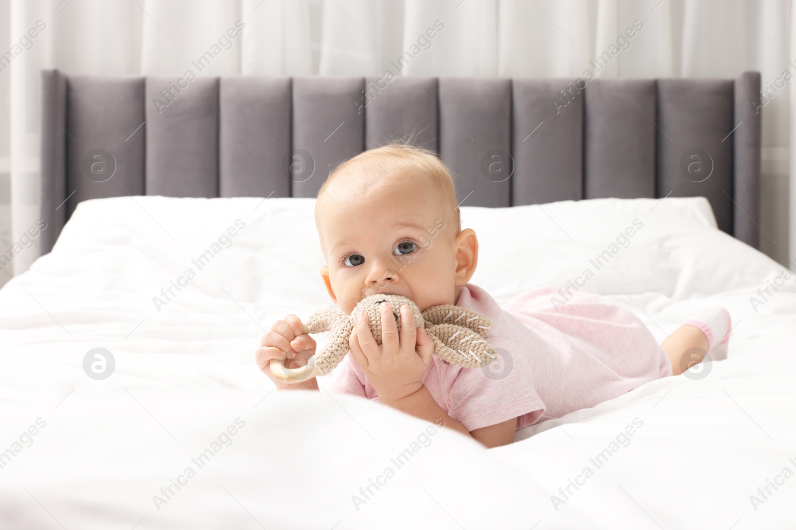 Photo of Cute little baby with rattle on bed indoors