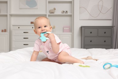 Photo of Cute little baby with rattles on bed indoors