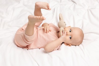 Photo of Cute little baby with rattle on bed indoors