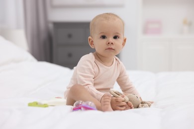 Photo of Cute little baby with rattles on bed indoors