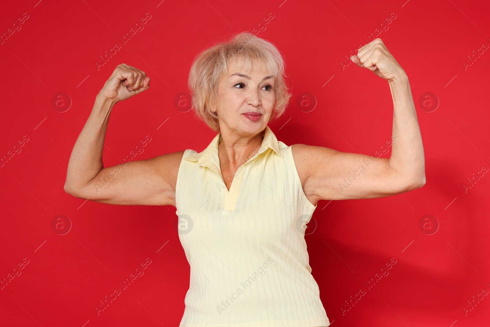 Photo of Senior woman exercising on red background. Healthy lifestyle