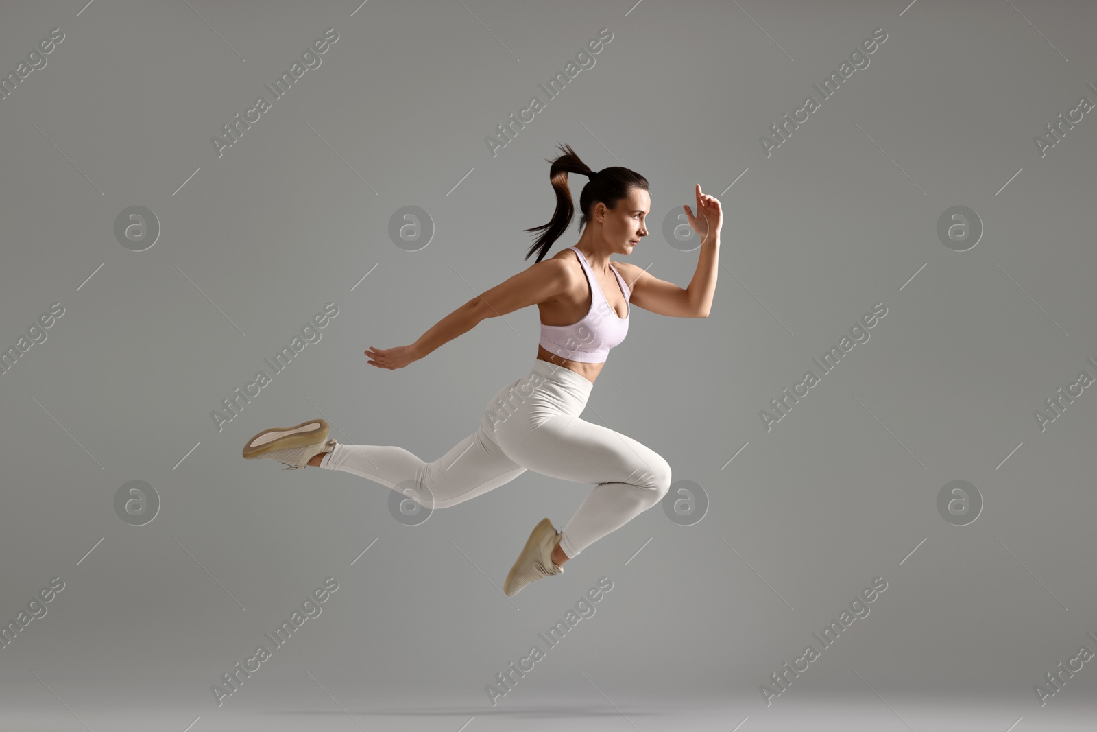 Photo of Woman in gym clothes doing exercise on grey background