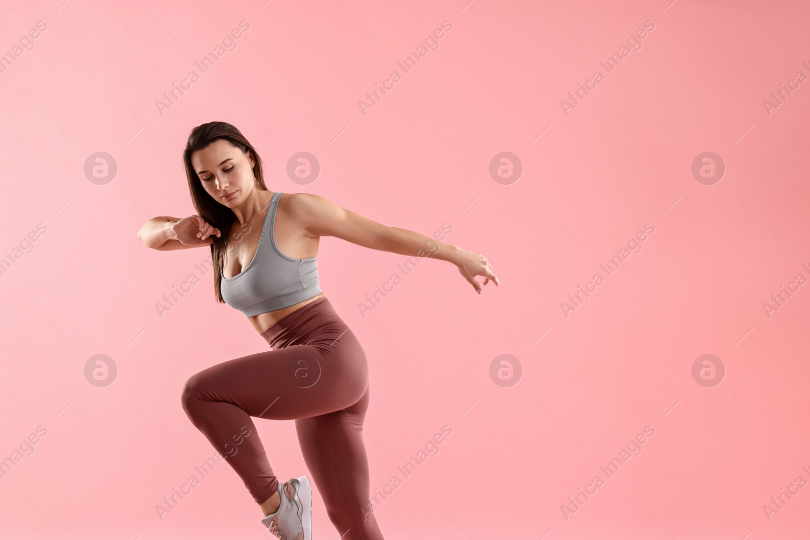 Photo of Woman in gym clothes doing exercise on pink background, space for text