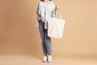 Photo of Woman with blank shopper bag on color background, closeup. Mockup for design