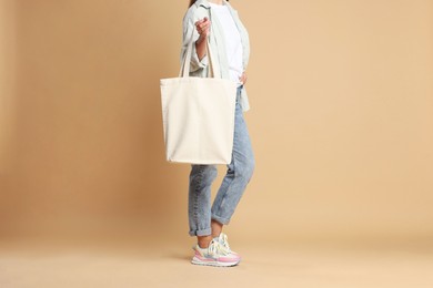 Photo of Woman with blank shopper bag on color background, closeup. Mockup for design