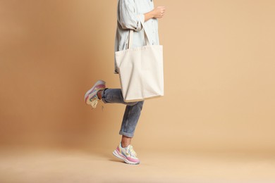 Photo of Woman with blank shopper bag on color background, closeup. Mockup for design