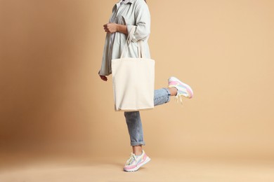 Photo of Woman with blank shopper bag on color background, closeup. Mockup for design