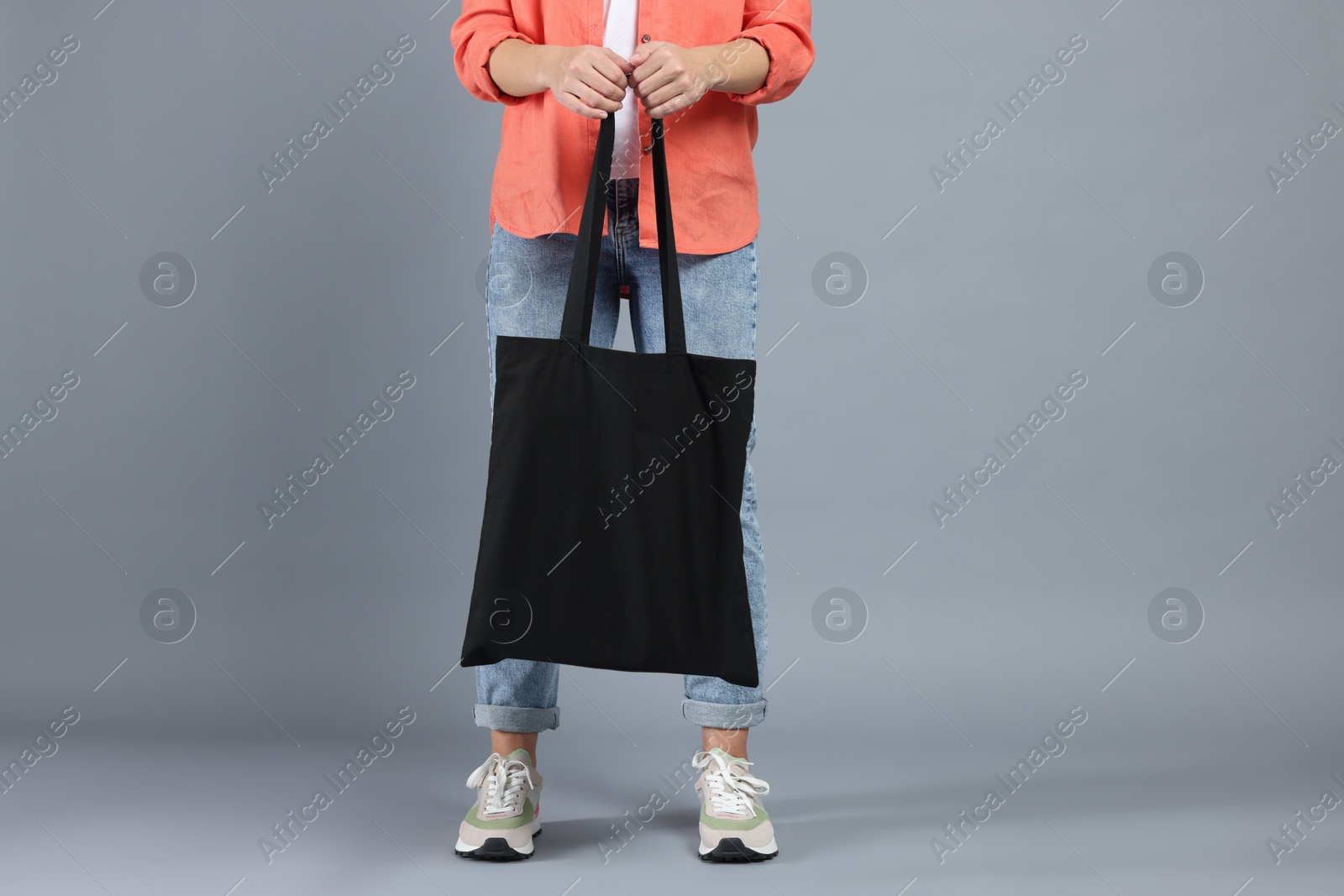 Photo of Woman with blank black shopper bag on grey background, closeup. Mockup for design