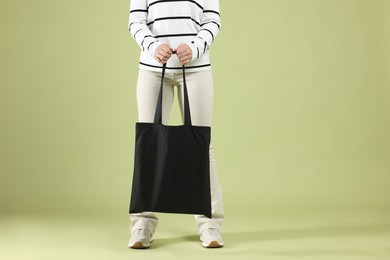 Photo of Woman with blank black shopper bag on color background, closeup. Mockup for design