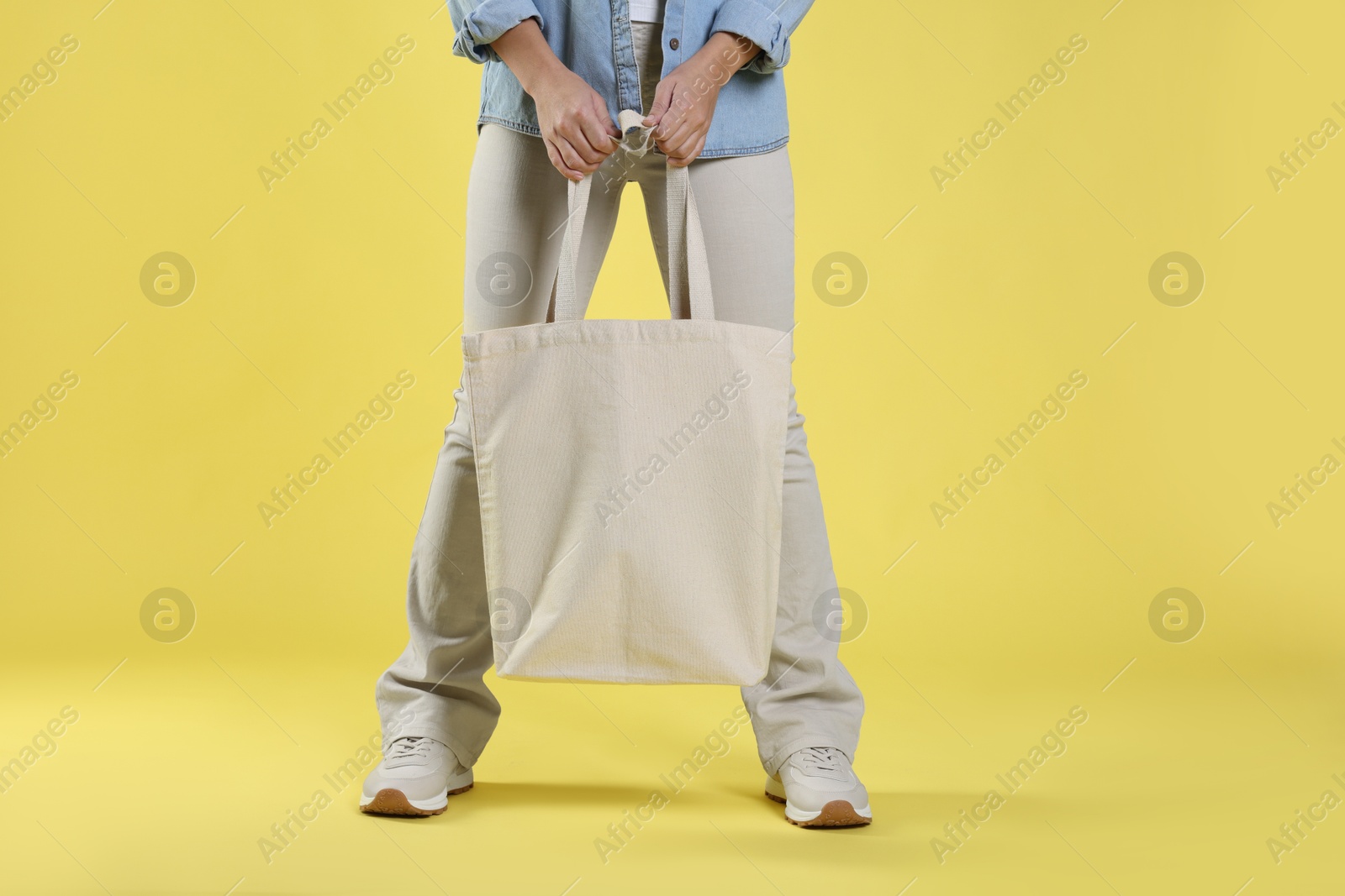 Photo of Woman with blank shopper bag on yellow background, closeup. Mockup for design