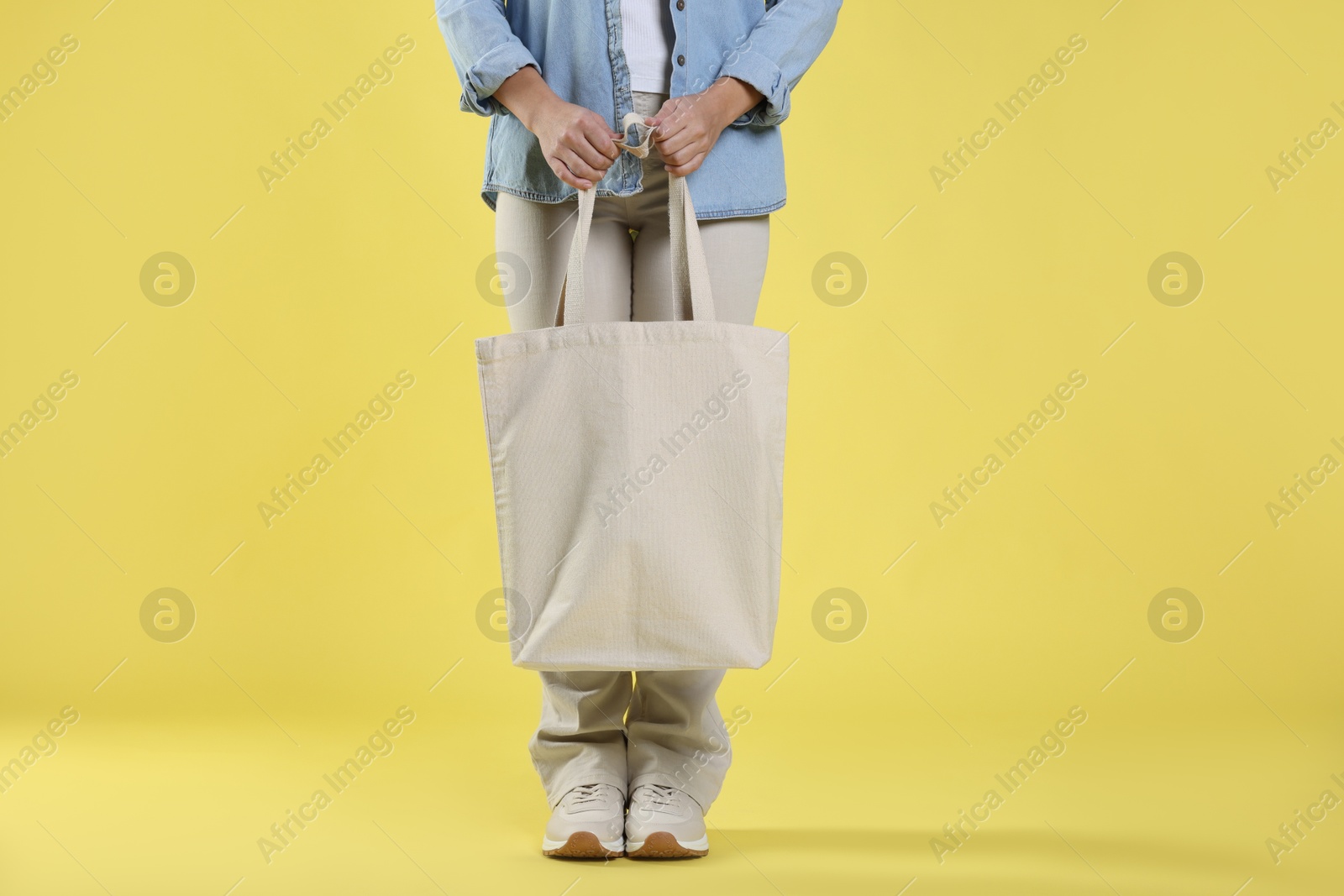 Photo of Woman with blank shopper bag on yellow background, closeup. Mockup for design