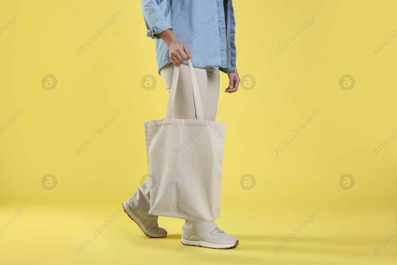 Photo of Woman with blank shopper bag on yellow background, closeup. Mockup for design