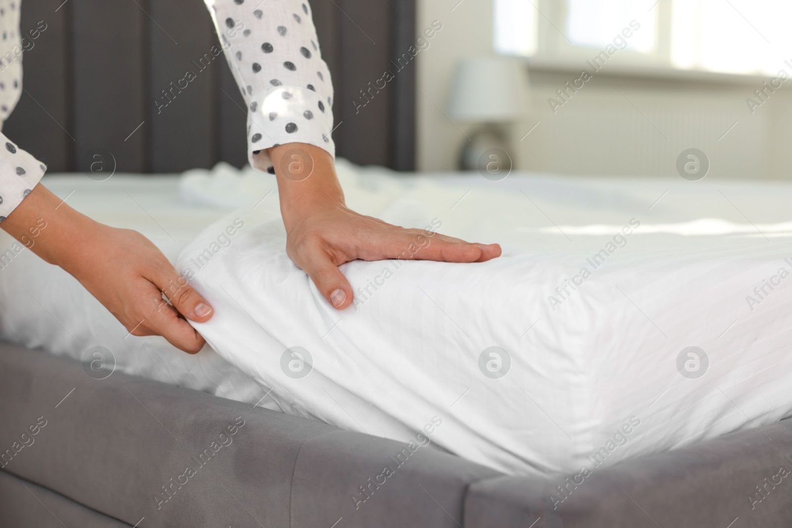 Photo of Woman changing clean bed linens at home, closeup