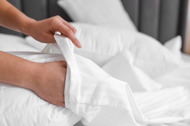 Photo of Woman changing clean bed linens at home, closeup