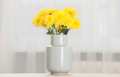 Photo of Beautiful yellow flowers in vase on table at home