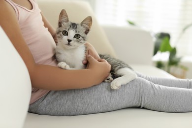 Photo of Little girl with cute kitten at home, closeup