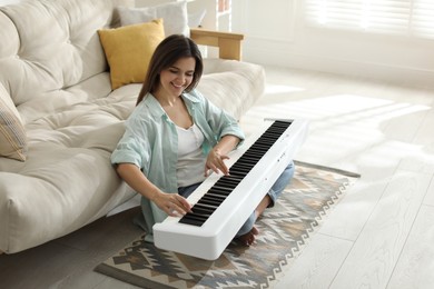 Photo of Smiling woman playing synthesizer on floor at home. Space for text