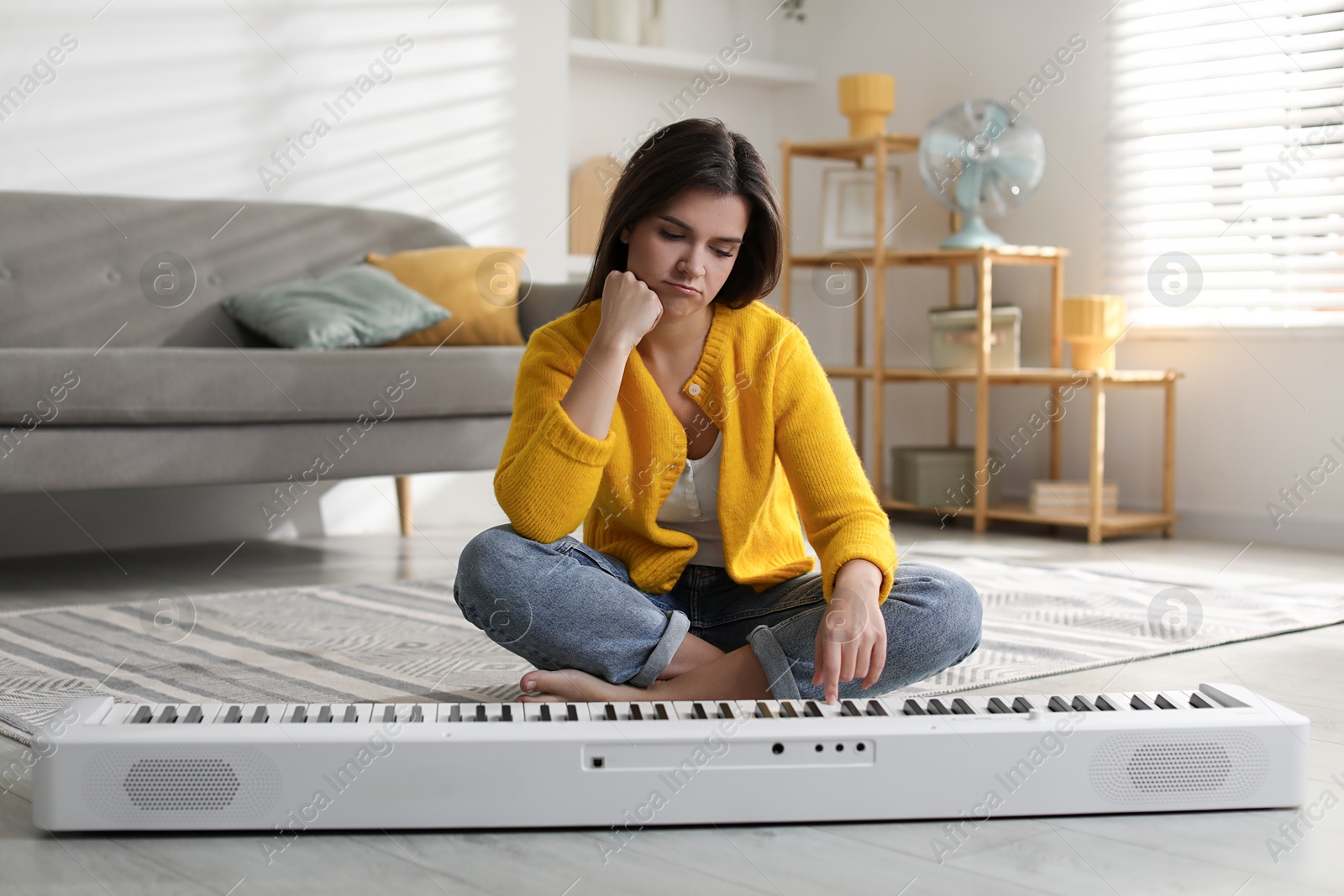 Photo of Upset woman near synthesizer on floor at home