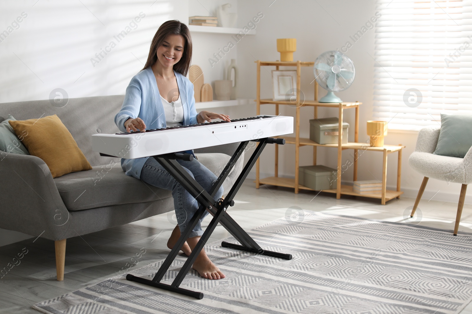 Photo of Smiling woman playing synthesizer at home. Electronic musical instrument